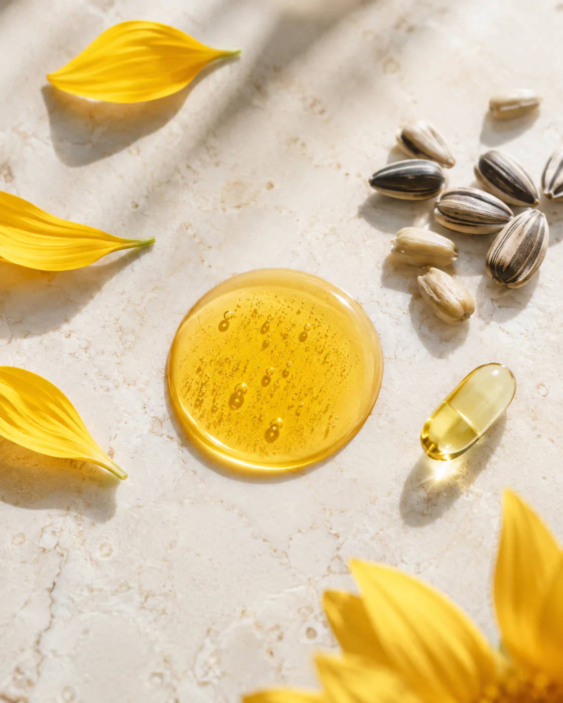 Olio di girasole ozonizzato OZOILAB con petali, semi di girasole e capsula su pietra chiara